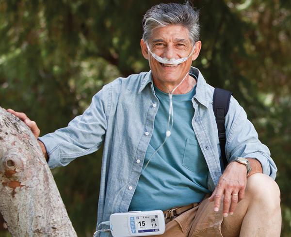 Patient outdoors wearing portable breathing device