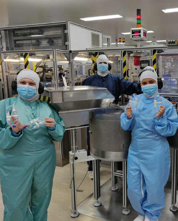 Baxter employees, gowned and masked, display medical products