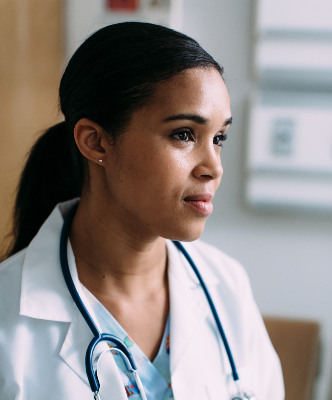 A doctor in a hospital room looks off to the side