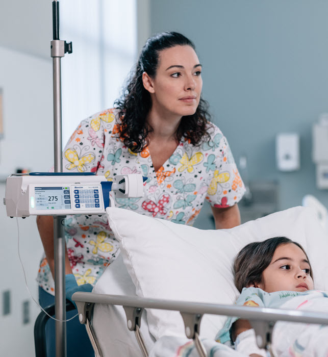 A healthcare provider pushes a young patient in a hospital bed
