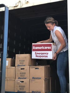 Woman unloading boxes of medical supply from a truck