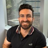 A man sits at his desk smiling