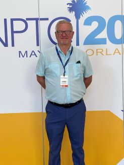 man standing in front of a sign at a convention
