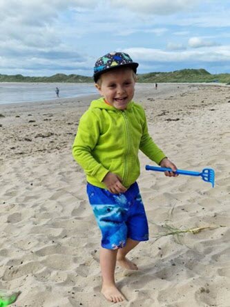 Child holds a toy shovel at the beach