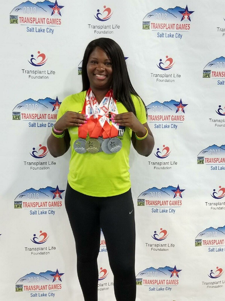 A woman stands outside holding her medals