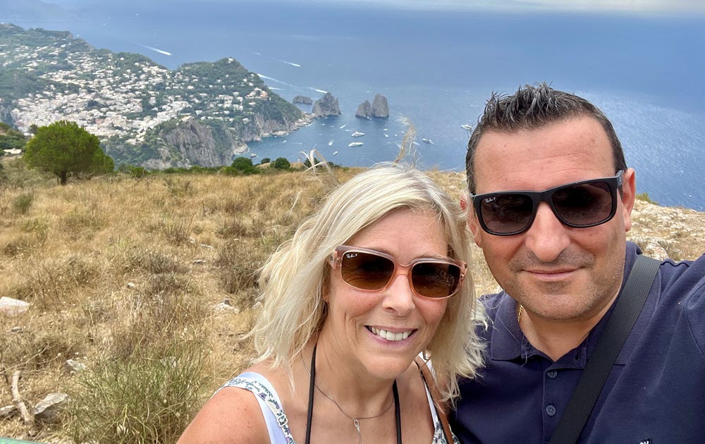 Baxter leader and his wife standing outside with mountains and water in the background