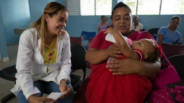 Clinician talking with patient who is holding a child