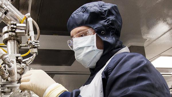 Image of a Baxter manufacturing employee in personal protective equipment working