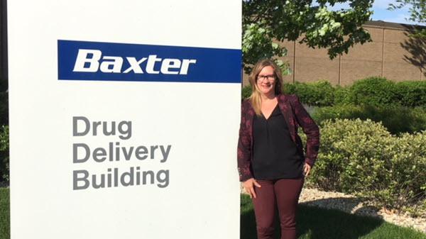 Image of a Baxter employee standing next to Baxter signage