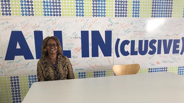 Employee poses in front of inclusive signage