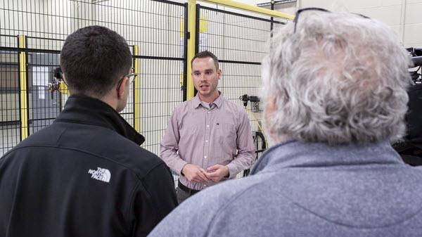 An engineer talks with two people during a tour.