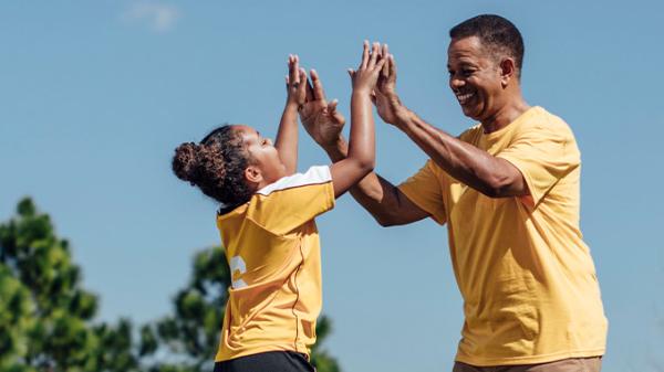 A father and his daughter celebrate on a soccer pitch