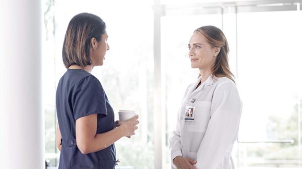Two healthcare professionals have a discussion in the hospital hallway