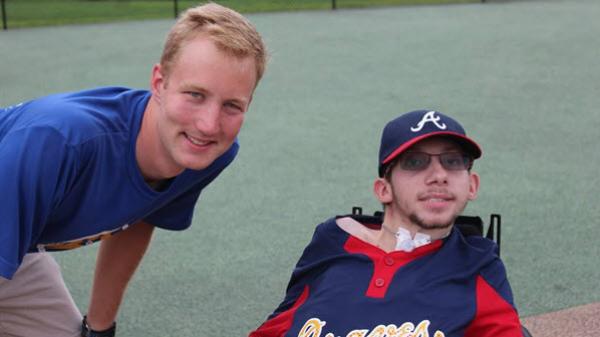 A Baxter employee stands next to another person who is in a wheelchair