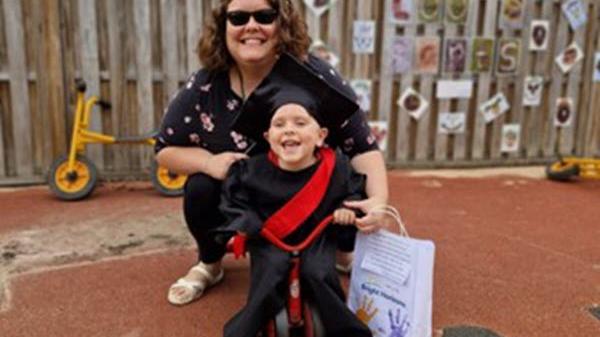 Employee sits next to son for a photo outside