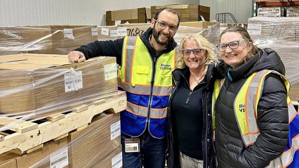 Baxter employees standing next to a pallet of boxes of Baxter supplies