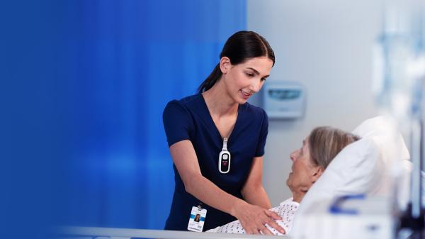 a nurse helps a patient while wearing a Voalte Linq device