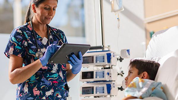 A clinician accesses data on a tablet from the bedside of her pediatric patient
