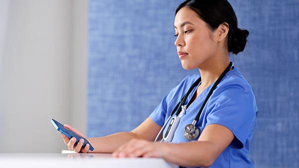 A clinician reviews data on a smartphone at a hospital nurse’s station