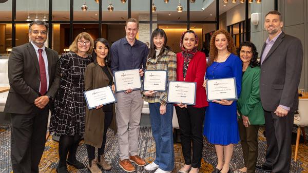 Group of professionals standing and holding certificates