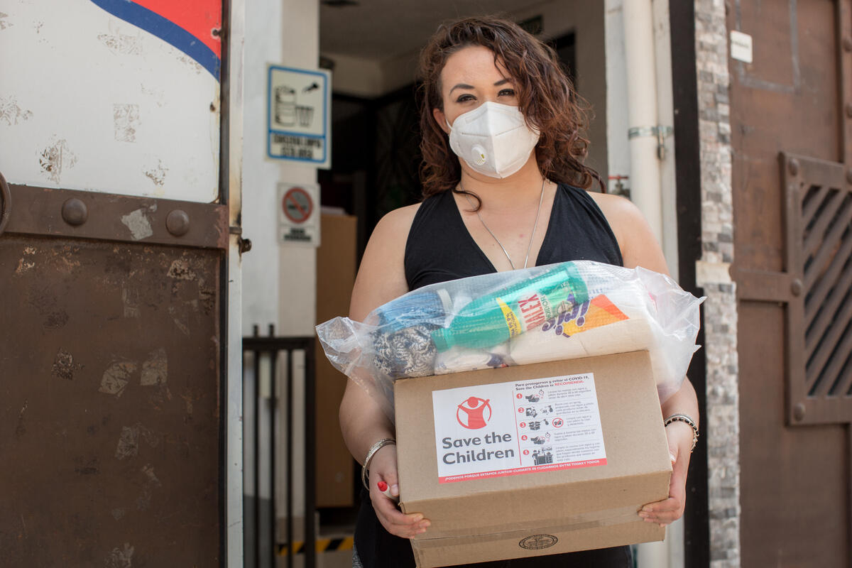 Women standing with supplies from Save the Children