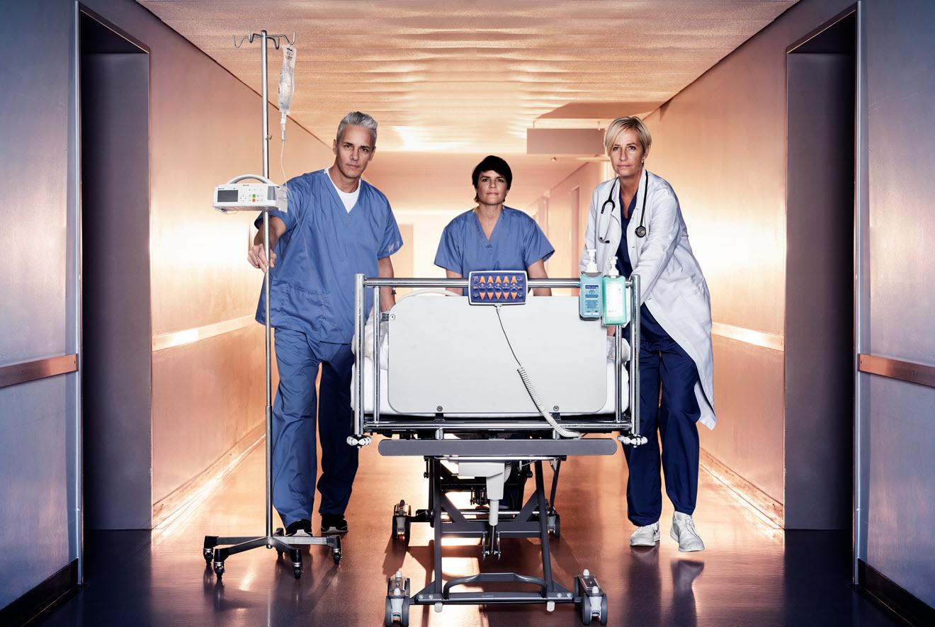 Healthcare professionals walking with hospital bed down a hallway
