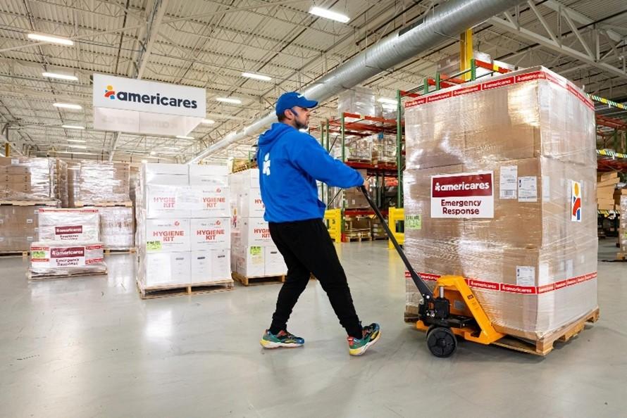 Worker uses a pallet mover to move boxes of product