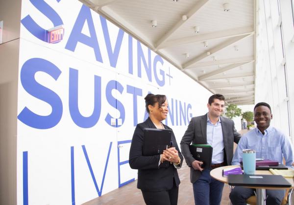 Baxter Employees in front of Save and Sustain wall