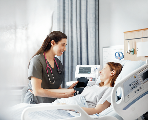 Patient in a hospital bed with healthcare professional at bedside