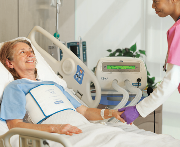 Patient wearing vest in a hospital bed with healthcare professional at bedside