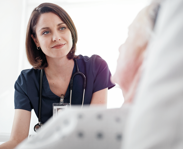 Healthcare professional sitting next to a patient in a hospital bed