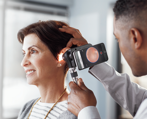 Healthcare professional using a medical device to look into a patient's ear
