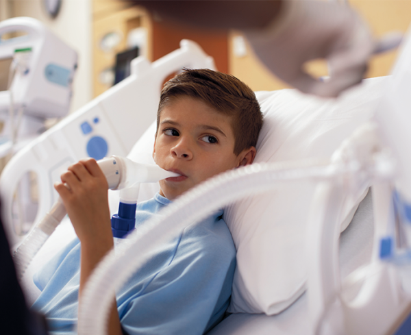 Young patient using a medical device in a hospital bed