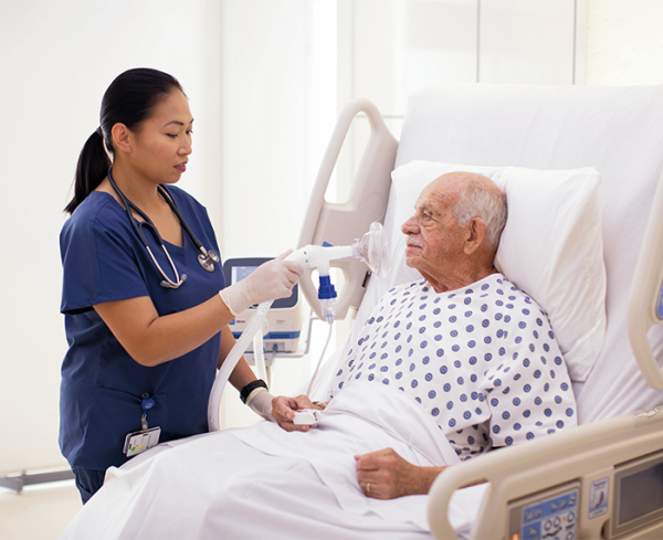 Healthcare professional assisting a patient in a hospital bed