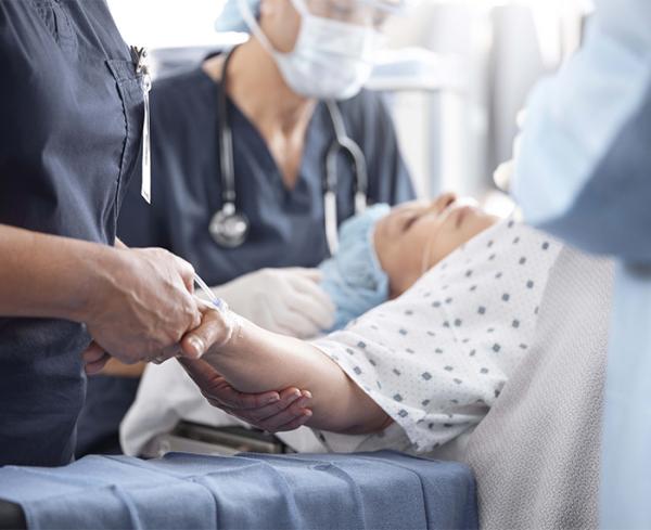 A surgeon holds the hand of a patient in the OR