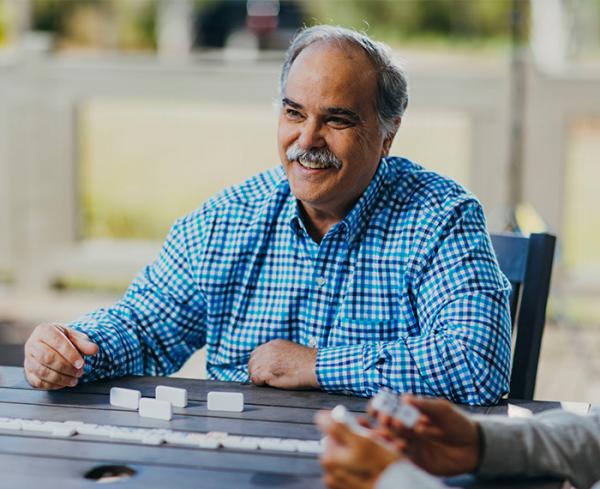 A man plays a board game outdoors at a table