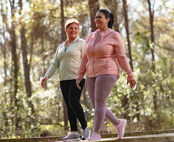 Two women take a walk in the forest wearing workout clothing