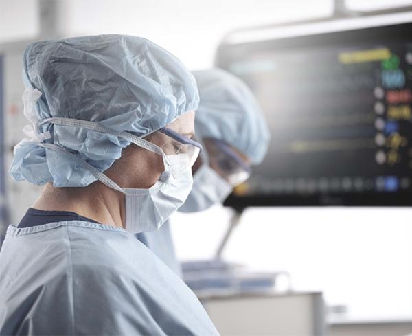 Two surgeons stand in front of a monitor in the operating room