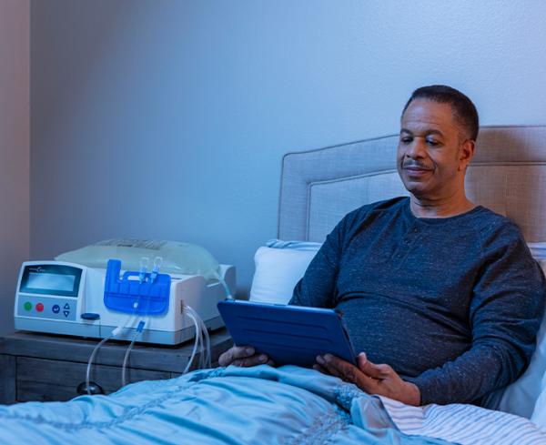 A man reads in bed next to his APD system