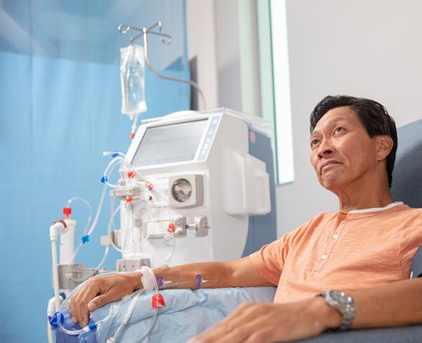 A man sits in a chair as he receives HD therapy from the HD device next to him. 