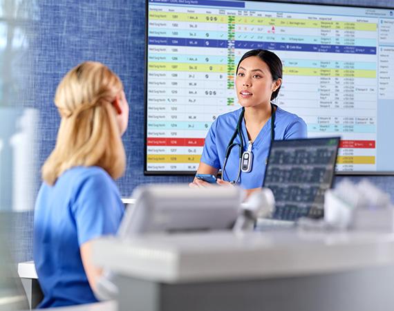 two nurses interact at the nurse station