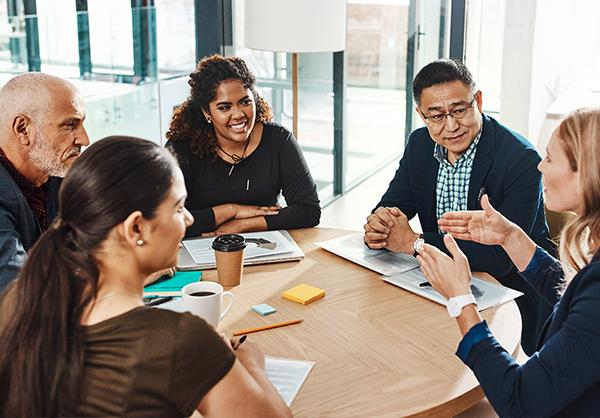a group of employees collaborate while seated at a table