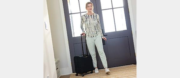 a woman walks with a luggage-style carrying case with 4-wheel spinner design