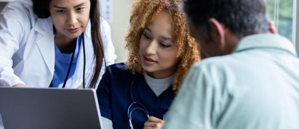 Two clinicians and a patient reviewing results on a laptop