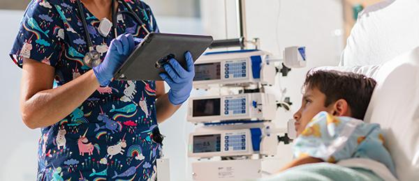A clinician accesses data on a tablet from the bedside of her pediatric patient