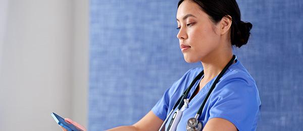 A clinician reviews data on a smartphone at a hospital nurse’s station
