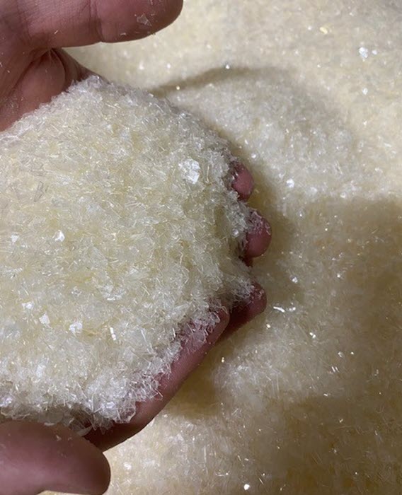 A person holds small pellets of recycled platic
