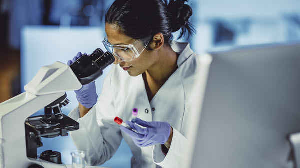 Research scientists looks into a microscope