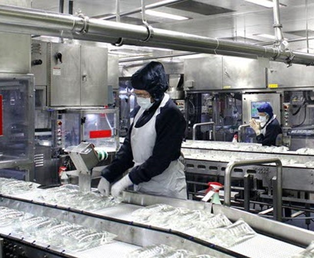 Image of an employee inspecting IV bags at a plant