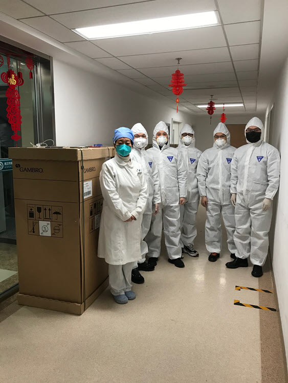 Baxter employees dressed in personal protective gear pictured in a hallway.